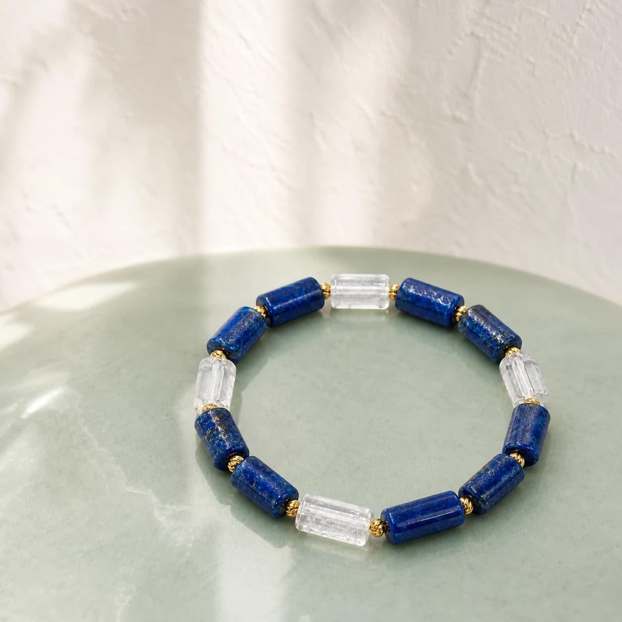 Lapis lazuli and clear quartz bracelet styled on a pale celadon ceramic surface
